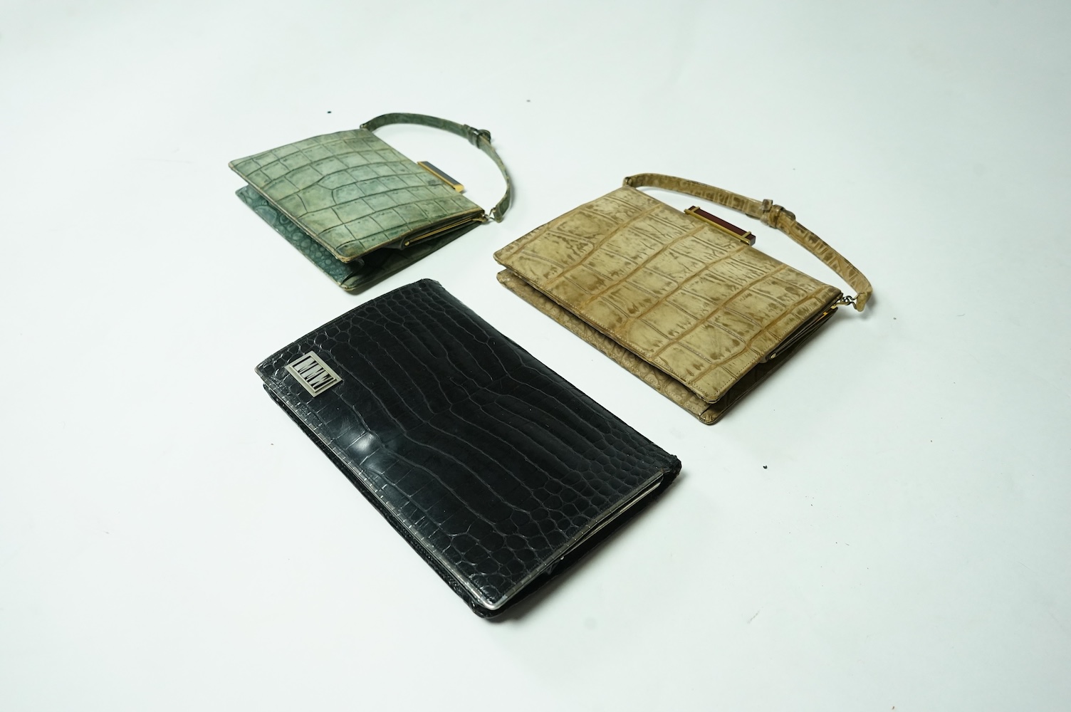Three stylish Art Deco ladies handbags. A black crocodile clutch bag with an MMW monogram and silver mounted edge and two smaller handbags, one green the other brown, both faux crocodile with stylish bakelite clasps. Clu
